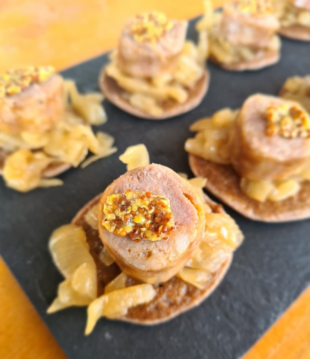 Médaillons de viande, oignons confits et moutarde à l’ancienne sur blinis